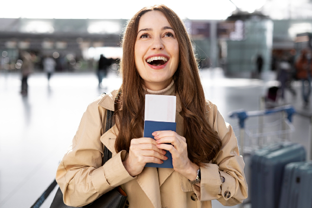 Mulher sorridente segurando passaporte e bilhete de avião em aeroporto
 Mulher sorridente segurando passaporte e bilhete de avião em aeroporto